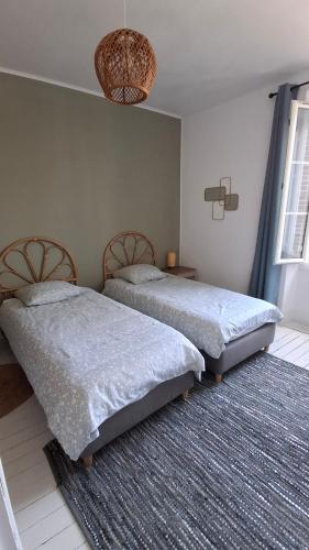 a bedroom with two beds and a rug at Le Gîte du Cerisier in Gy-les-Nonains