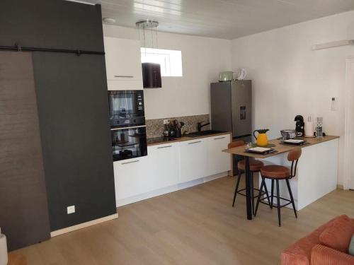 a kitchen with white cabinets and a table with chairs at Le Temps des Cerises in La Cresse