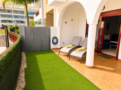a garden with a bench and grass on a patio at Oasis Palm Mar by HelloApartments in Palm-Mar
