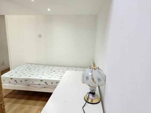 a white room with a bed and a lamp at Shriji Homes in Watford West Station