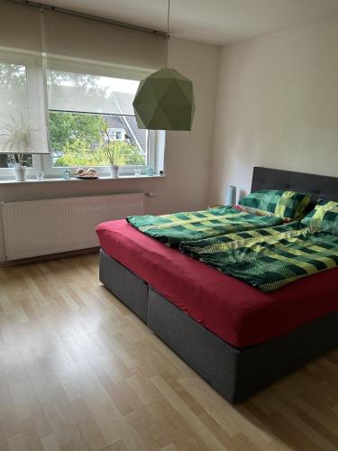 a bedroom with a bed with a red comforter and a window at Modern feel-good apartment in Bad Lippspringe