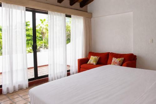 a bedroom with a bed and a couch and windows at The White Villa in Cancún