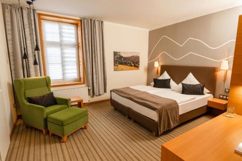 ein Hotelzimmer mit einem Bett und einem grünen Stuhl in der Unterkunft DIEDRICH Wellnesshotel & Spa - Adults only in Hallenberg