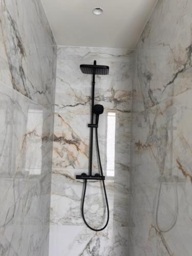 a shower in a bathroom with a marble wall at The Corner-GILBERT in Oedelem