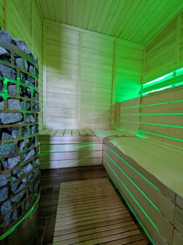 a sauna with green lights in a wooden room at Kierunek Puszcza 2 Apartamenty - Balia, Sauna, Grota solna - max 14 osob in Narewka