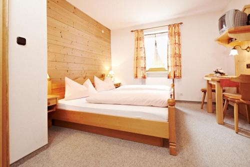 a bedroom with a bed and a desk and a window at Gästehaus Sonnenbichl in Fischbachau