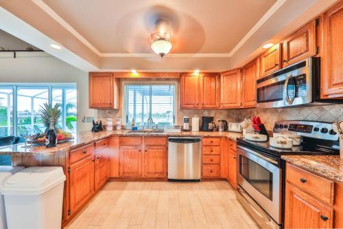 a large kitchen with wooden cabinets and a window at Island Paradise Villa RNT-01125 in Cape Coral