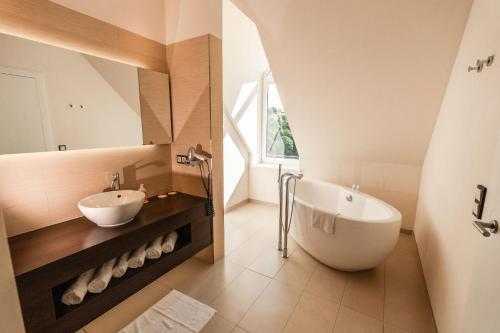 ein Badezimmer mit einer großen Badewanne und einem Waschbecken in der Unterkunft DIEDRICH Wellnesshotel & Spa - Adults only in Hallenberg