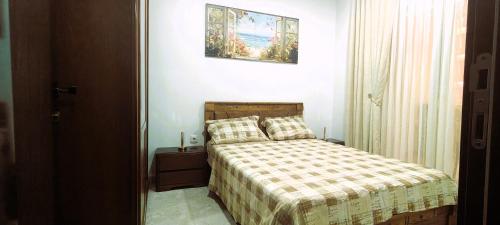 a small bedroom with a bed with a checkered blanket at Résidence nid d'abeille Béjaïa in Bejaïa