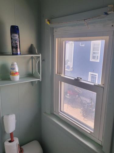 a window in a bathroom with a toilet and a house at ARMANI MANOR UPSTAIRS UNIT 3 quaint rustic 1br in Wildwood