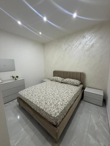 a bedroom with a bed and a white wall at Sikelia home in Giardini Naxos