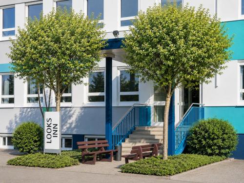 a building with two trees and benches in front of it at looks-inn in Viernheim