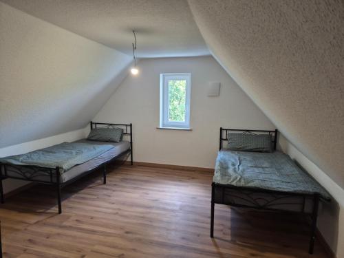 a attic room with two beds and a window at Ferienwohnung KEMS in Gundelsheim