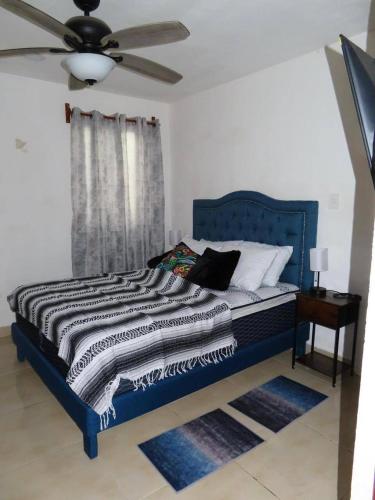 ein blaues Bett in einem Zimmer mit Deckenventilator in der Unterkunft Casa Las Brisas in Progreso