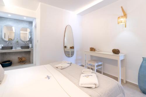 a white bedroom with a bed and a mirror at Saraya Resort in Alinda