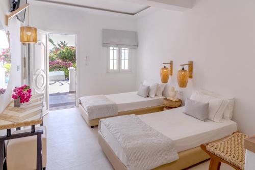 two beds in a white room with a balcony at Saraya Resort in Alinda