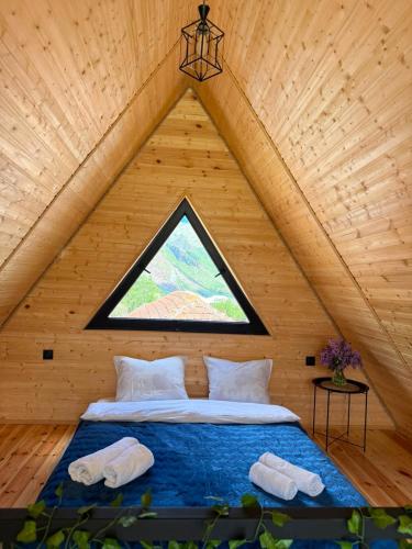 a bed in a wooden room with a window at Tobani Cottage Kazbegi in Kazbegi