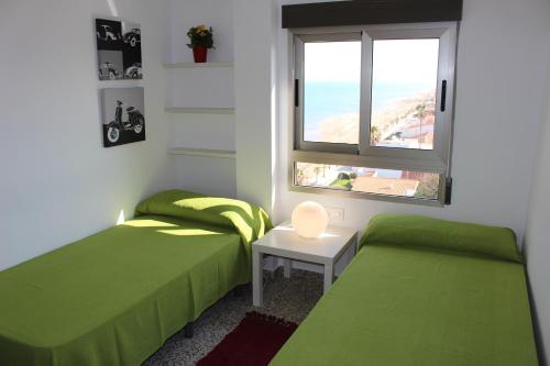 a bedroom with two green beds and a window at Apartamentos Guillem in Playa de Miramar