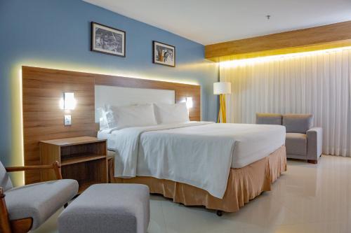 a hotel room with a large bed and two chairs at Holiday Inn Express Belem Ananindeua by IHG in Belém