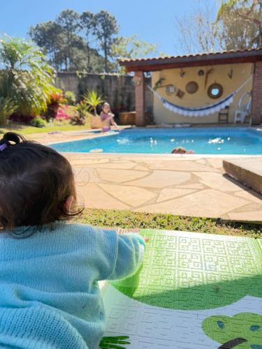 a little girl laying on the ground near a swimming pool at Chácara Nunes in Ibiúna