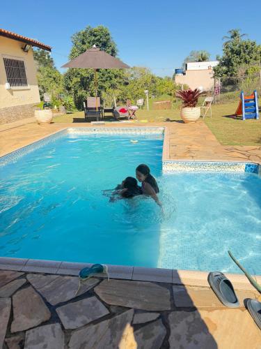 two people are swimming in a swimming pool at Chácara Nunes in Ibiúna