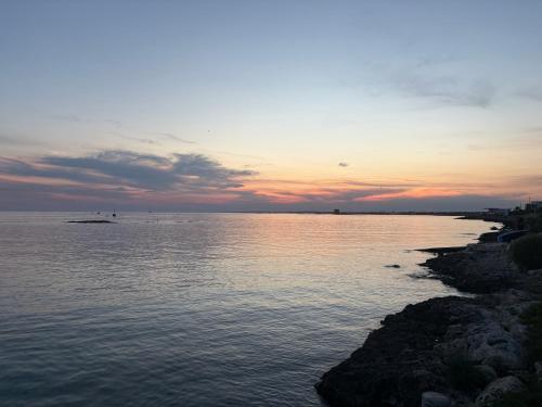 a large body of water with a sunset in the background at A casa di Marina Mare Centro posto auto in zona in Porto Cesareo