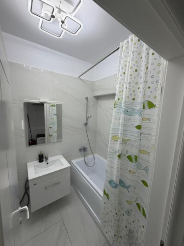 a white bathroom with a sink and a shower curtain at Apartament in Ploiești 7 in Ploieşti