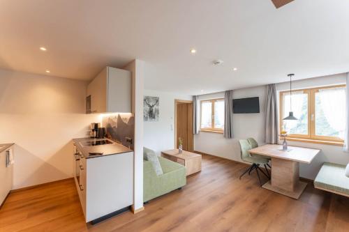 a kitchen and living room with a desk and a table at Hotel Hertehof in Damuls