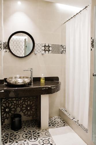 a bathroom with a sink and a mirror and a shower at Riad Zyna in Meknès