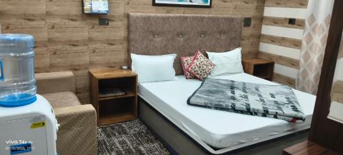 a small bedroom with a bed and a chair at Qasmi Hotel in Jammu