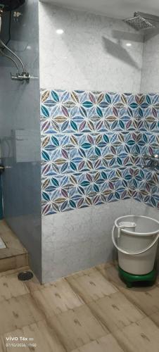 a bathroom with a toilet and a tiled wall at Qasmi Hotel in Jammu