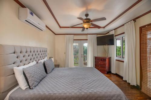 a bedroom with a bed and a ceiling fan at Exclusive House near West End & Beaches - Starlink in Roatán
