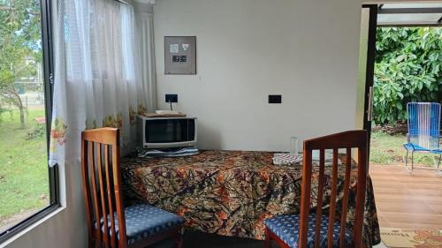 a bedroom with a bed with a tv and two chairs at Little Home in General Viejo