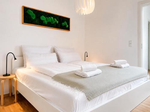 a white bed with towels on top of it at SCHEE Apartments - stilvolle & zentrale Wohnungen mit Privatparkplatz in Nördlingen
