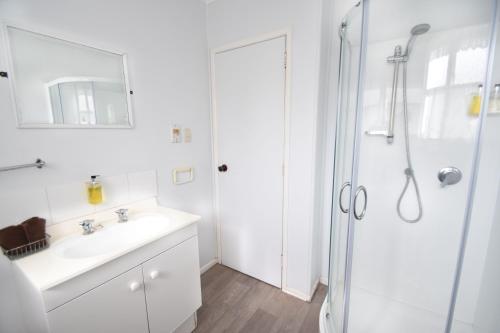 羅托魯阿的住宿－聯盟維多利亞汽車旅館，白色的浴室设有水槽和淋浴。