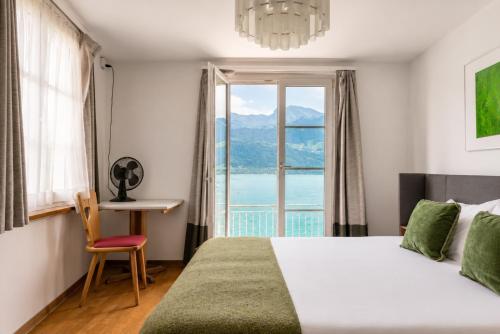 a bedroom with a bed and a table and a window at Seehotel Schwert in Gersau