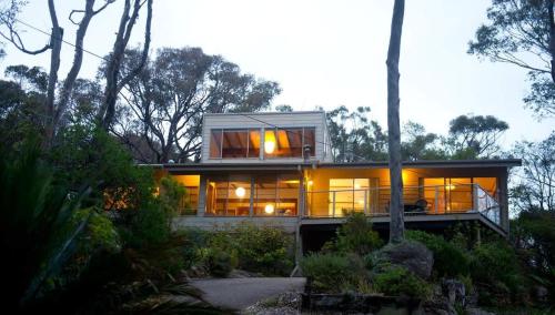 a house with large glass windows on a hill at Seascapes at Rosedale in Tomakin