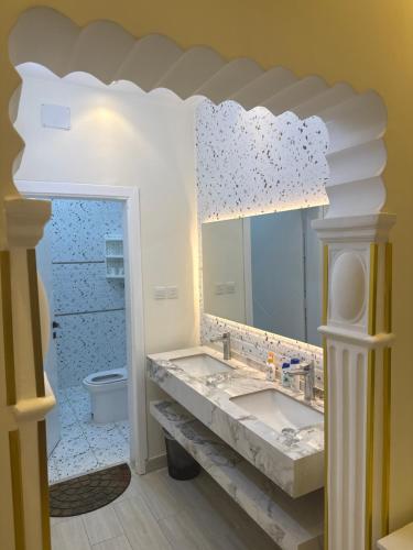 a bathroom with two sinks and a mirror at غرفة نوم 3 أسرّة مدخل خاص بدون صالة in Al Baha