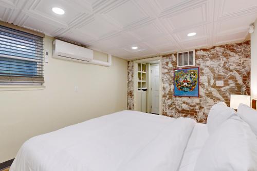 a bedroom with a white bed and a brick wall at Easy Access to OSU! 'Marvin's Manor' in Stillwater in Stillwater