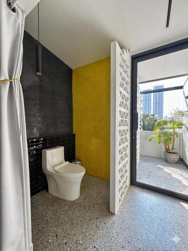 a bathroom with a toilet and a yellow wall at Siri Designer 3-Storey Townhouse with Garden and Luxury Amenities in Bangkok