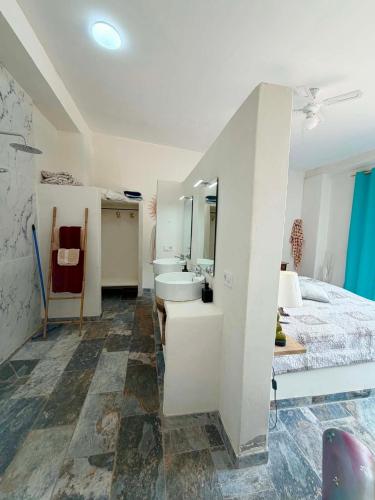 a white bathroom with a bed and a sink at Chambre d'hôtes in Ondara