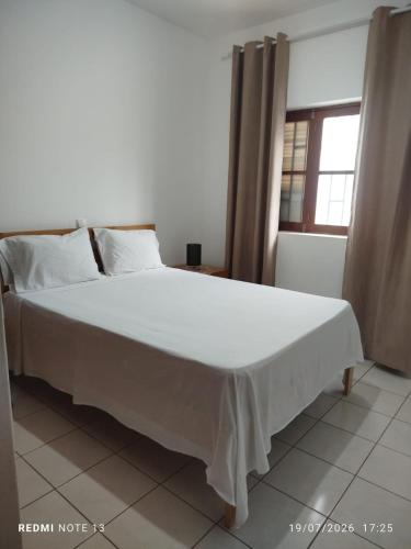 a large white bed in a room with a window at Kasa Tabuga in Porto Novo