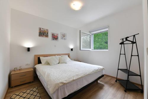 a white bedroom with a bed and a window at Guesthouse Spektar in Irinovac