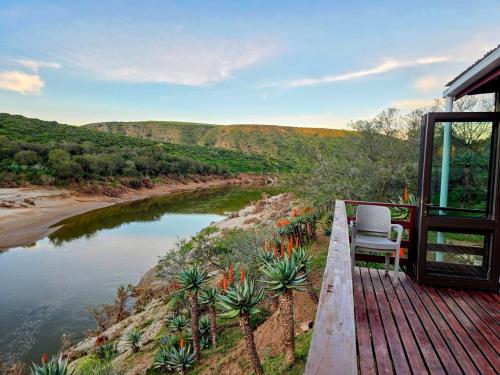 a chair sitting on a deck next to a river at Gourits River Guest Farm in Mossel Bay