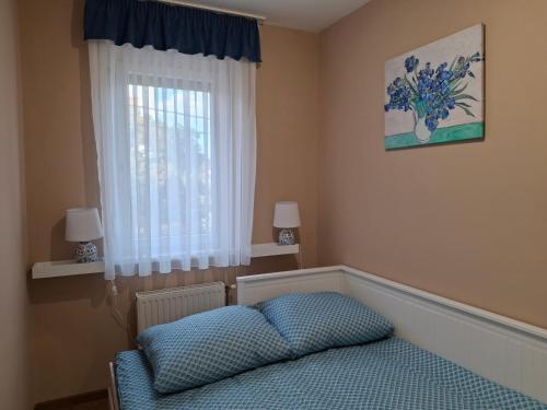 a bedroom with a blue bed and a window at Blue Iris Apartment in Kecskemét
