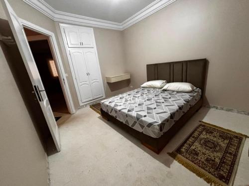 a bedroom with a bed with a wooden headboard at Appartement Bizerte Nord in Bizerte