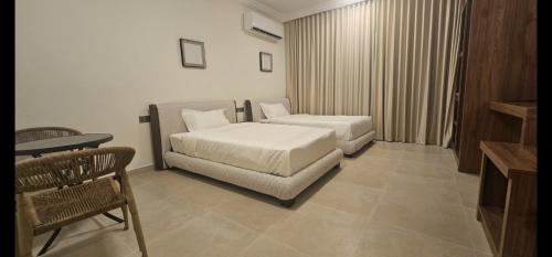 a bedroom with two beds and a chair and a table at Salalah Royals Residence in Daḩārīz