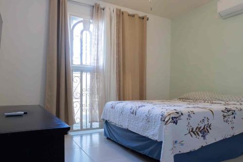 a bedroom with a bed next to a window at Playa Dorada 3BR Home with Beach Club, pools, Garden with BBQ in ArraijÃ¡n