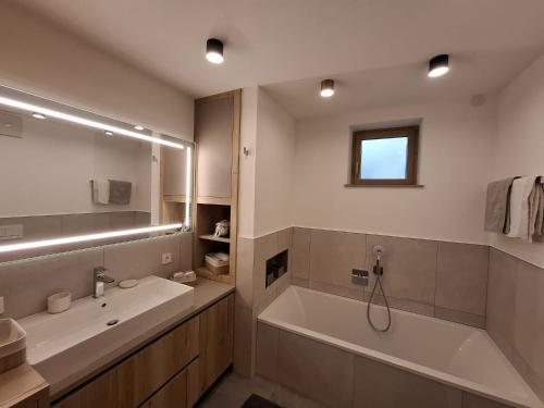 a bathroom with a tub and a sink and a mirror at Residence Wiesenheim in Trodena