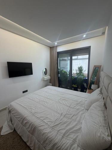 a bedroom with a large white bed and a window at Les belles terrasses mansouria in Mansouria